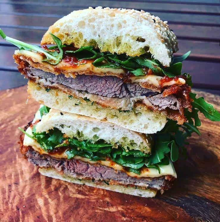Veal parm sandwich cut in half on wooden board