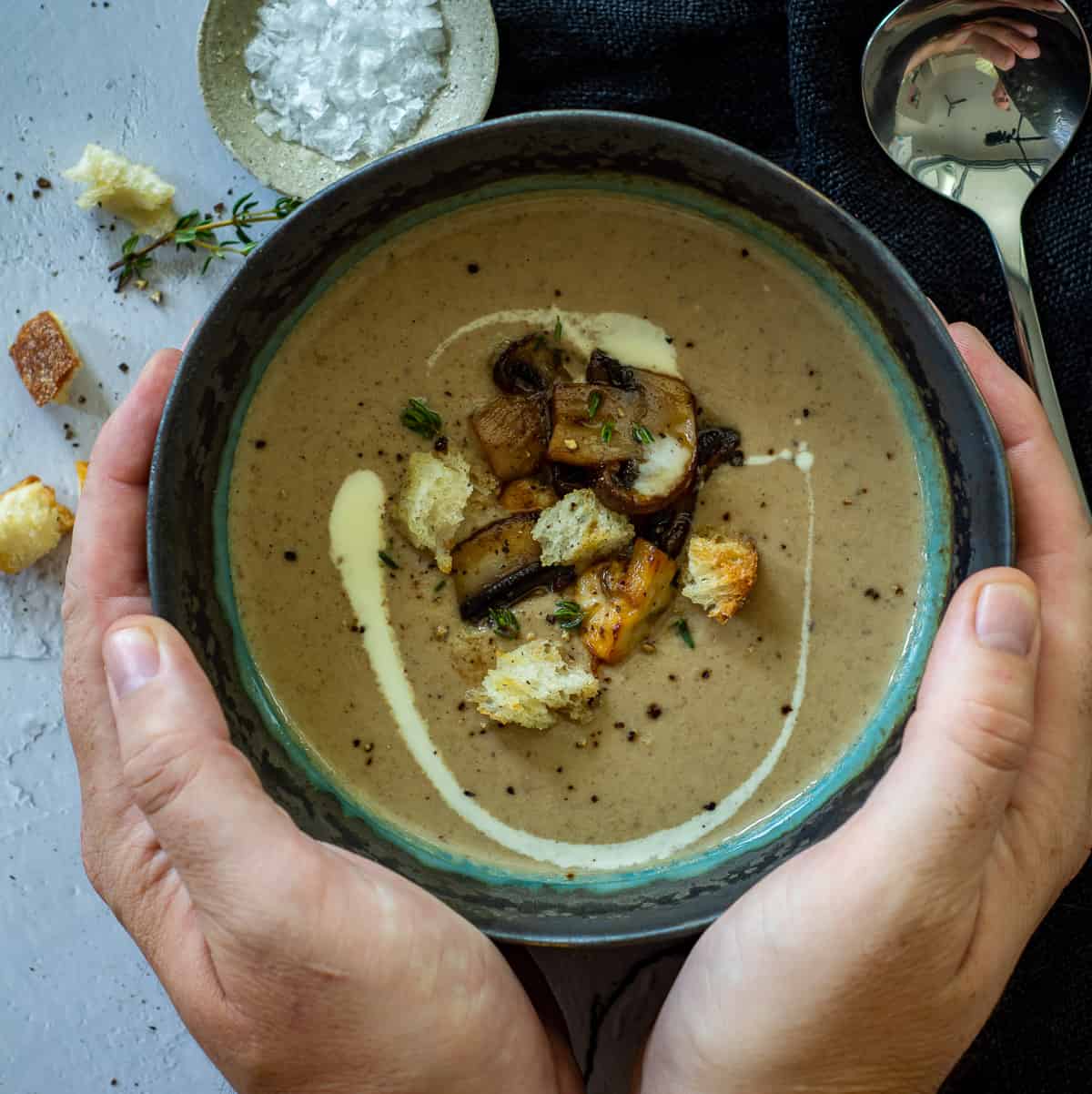 someone cupping a bowl of dried porcini mushroom parsnip soup