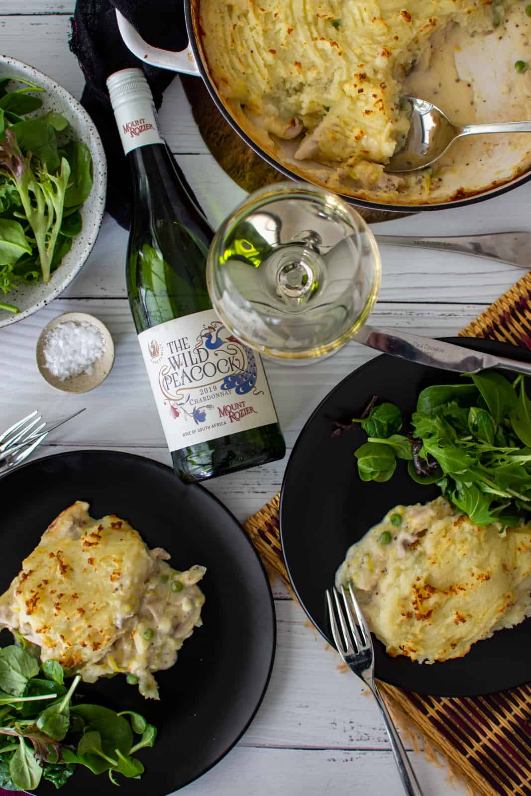 Chicken Mushroom Pie chicken and mushroom pie on plates with salad and a bottle of chardonnay next to them