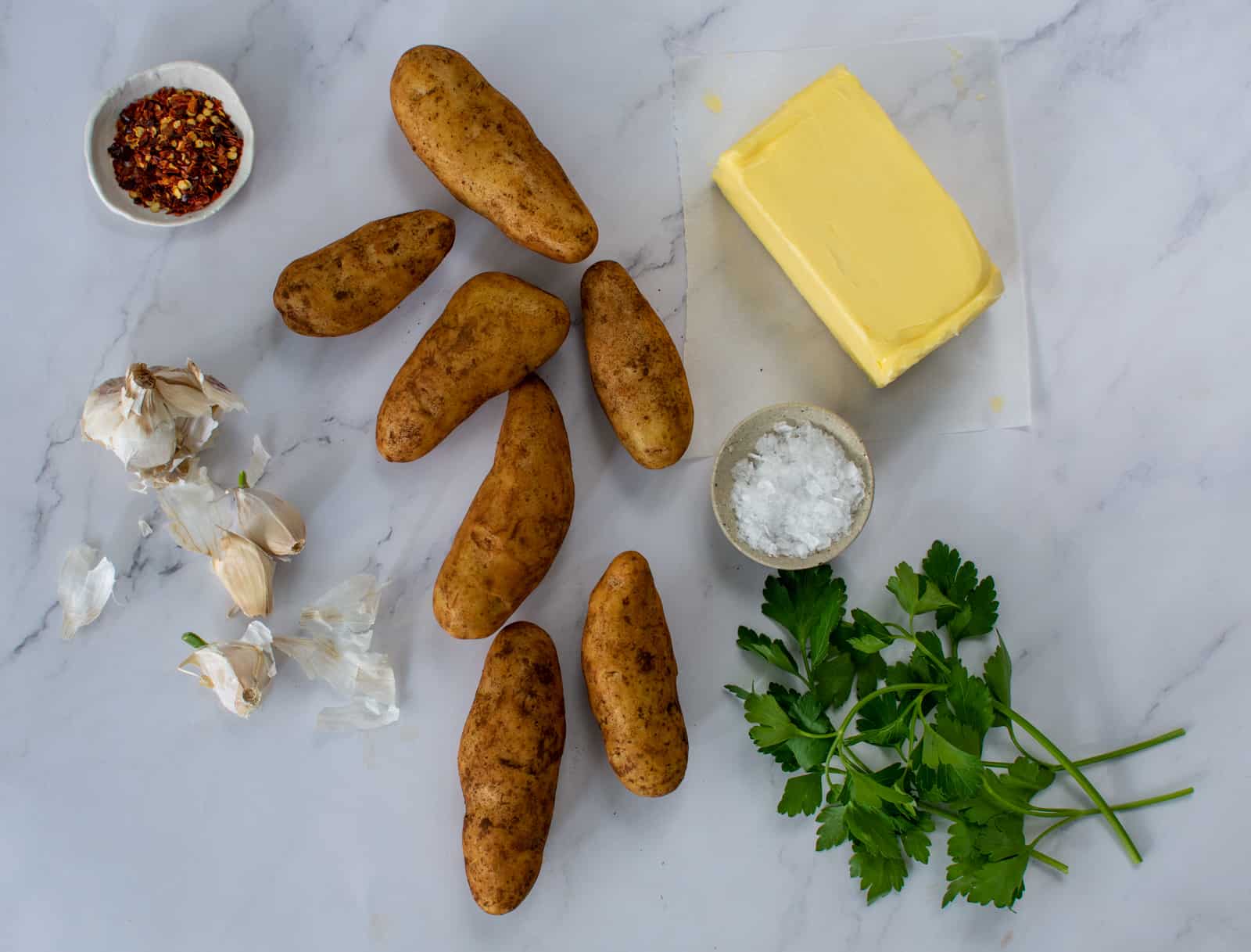 kipfler potatoes, butter, garlic and herbs on kitchen counter top 