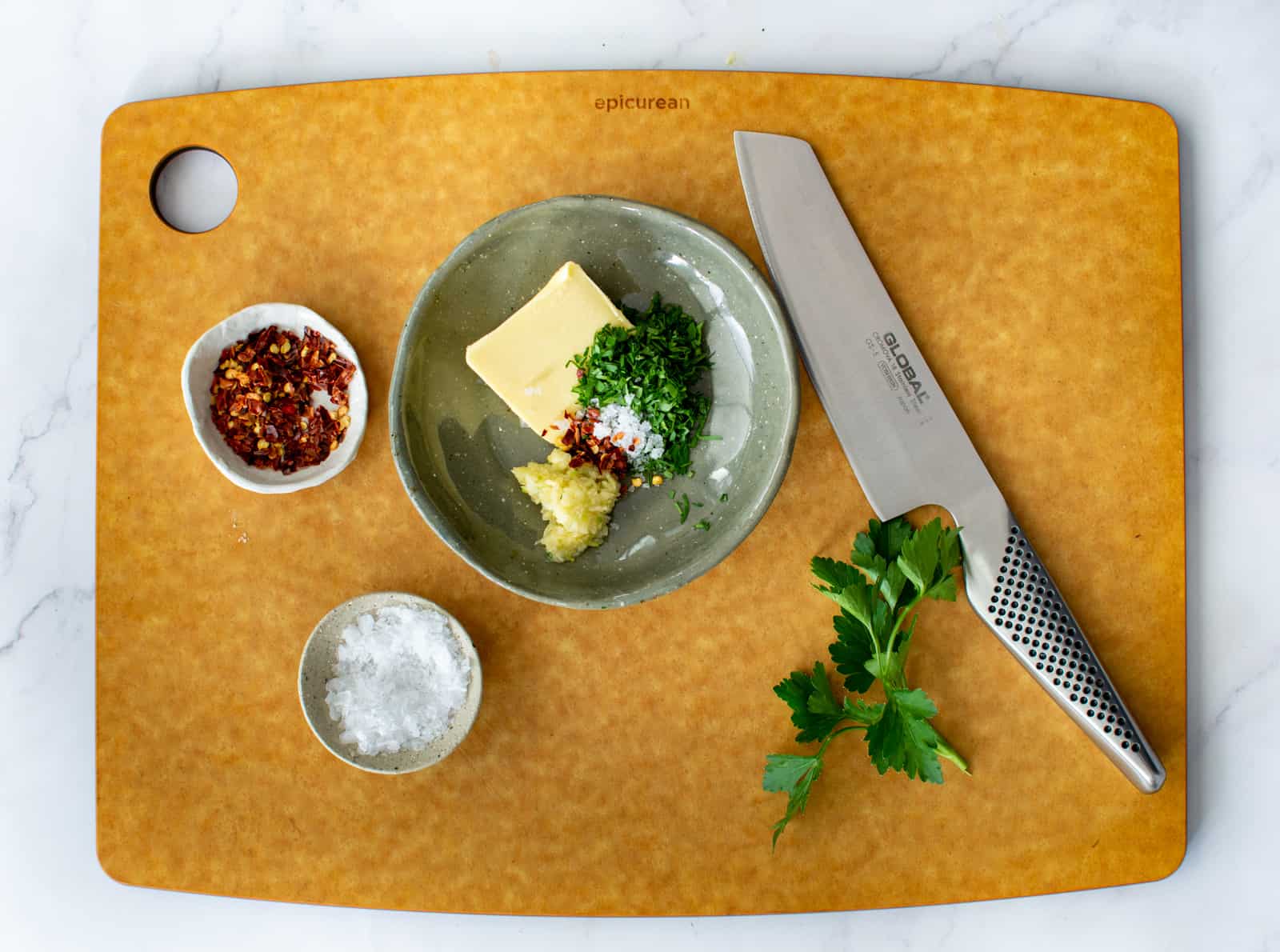 herbed butter in bowl with chef knife on chopping board 