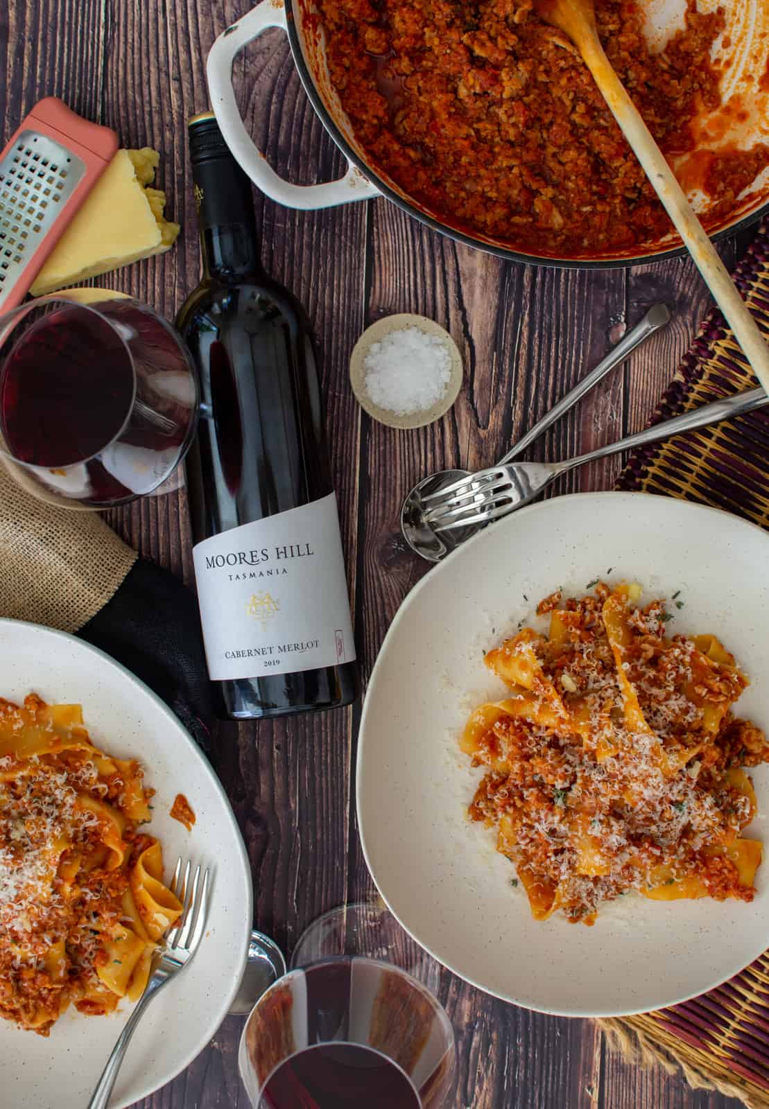 finsihed pork chorizo ragu in bowls, casserole dish and red wine on the table 