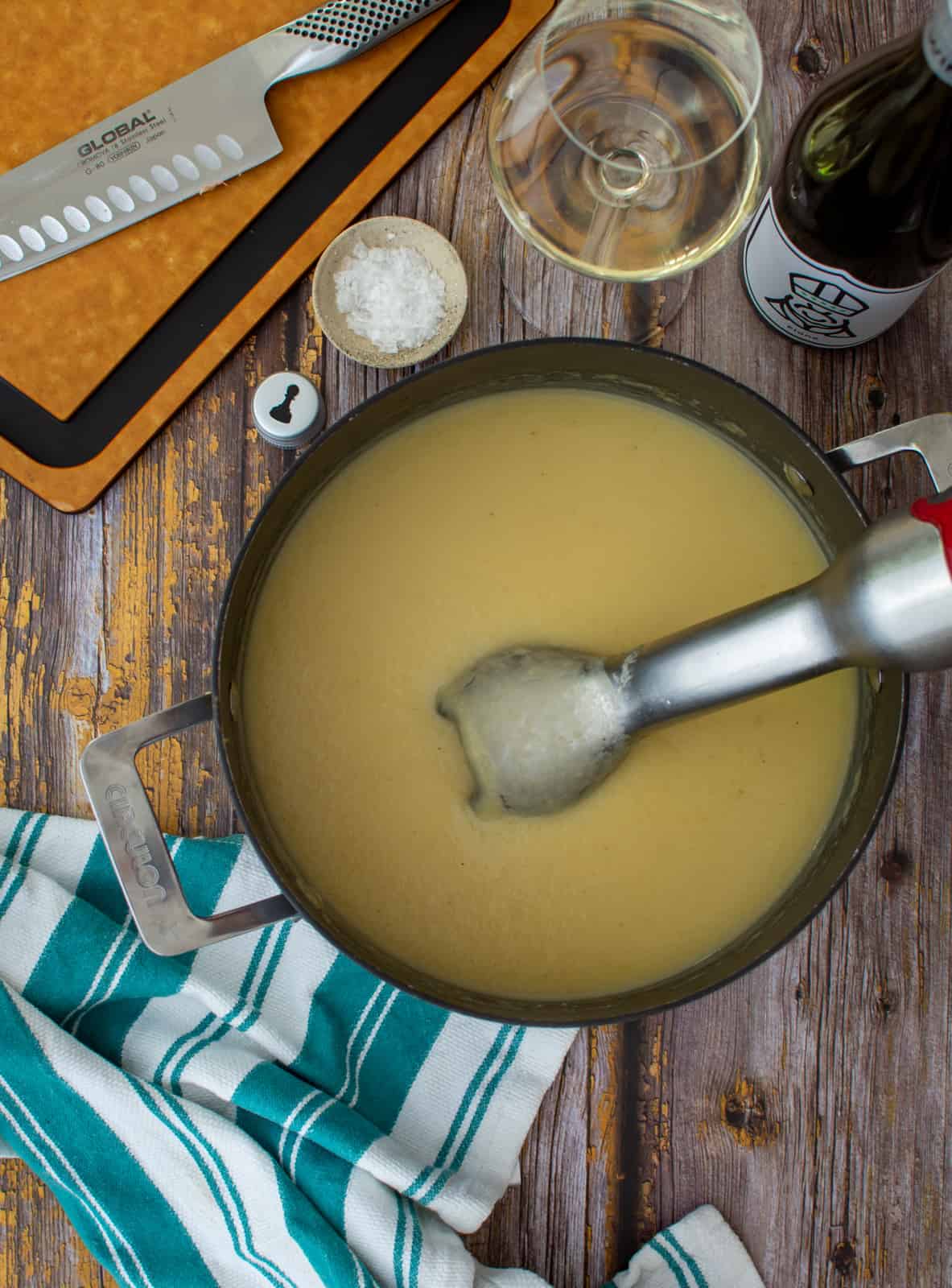 Parsnip soup in saucepan with a stick blender in it 