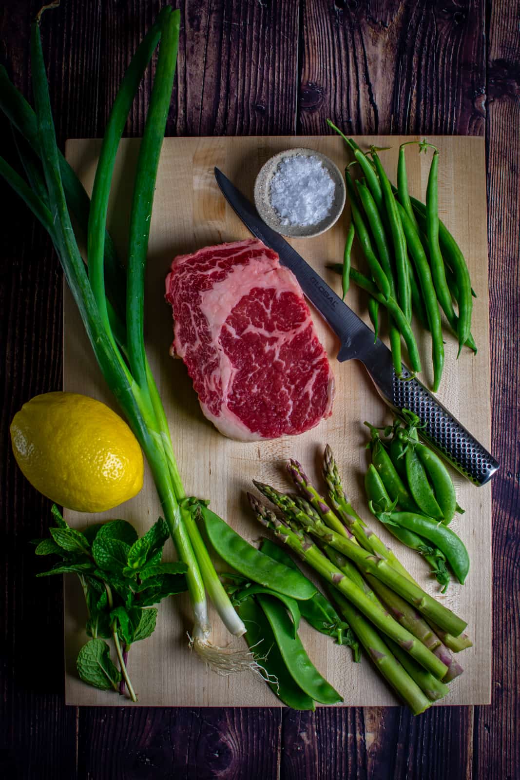 steak and mixed spring greens on a chopping board 