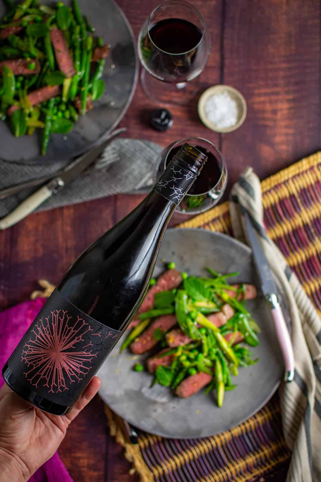 Red wine being poured with food blurred out beneath 