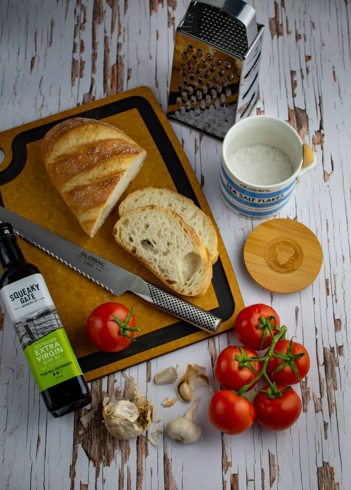Ingredients for pan con tomate on chopping board on table 
