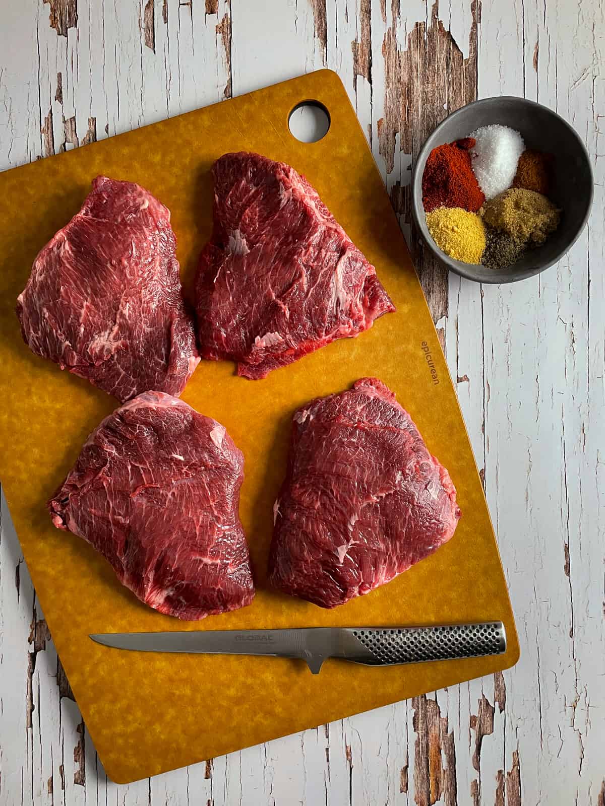 beef cheeks on chopping board and spices next to them 