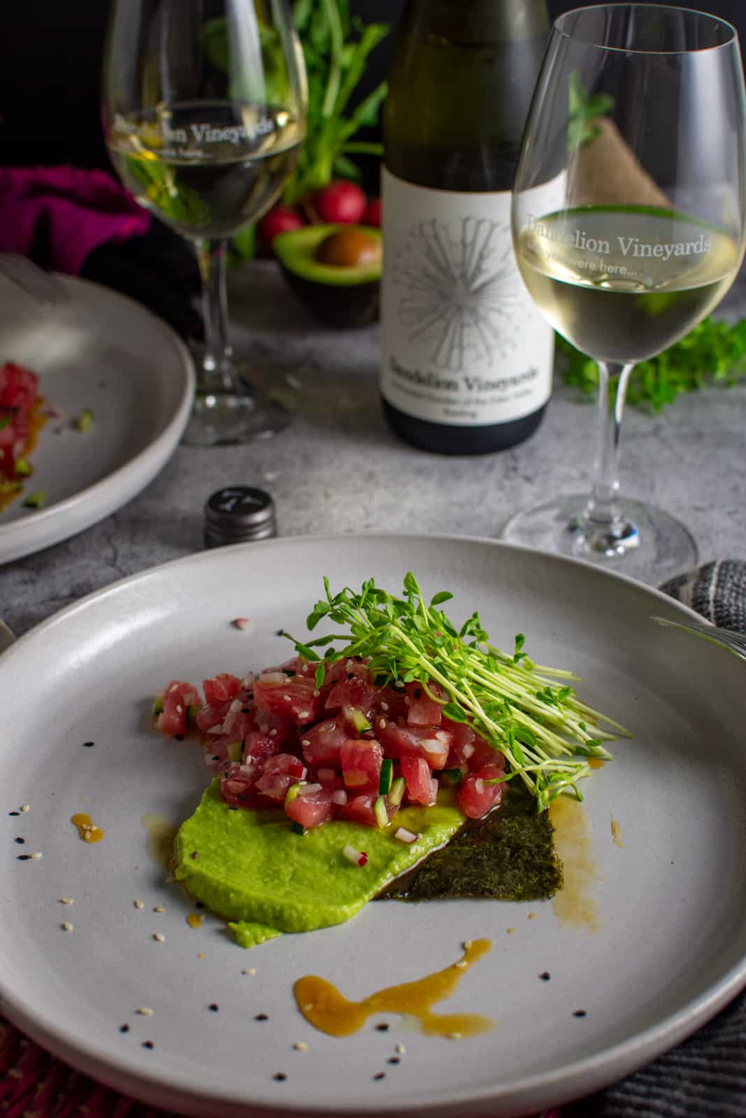 Tuna Crudo on white plates with dandelion riesling in background 