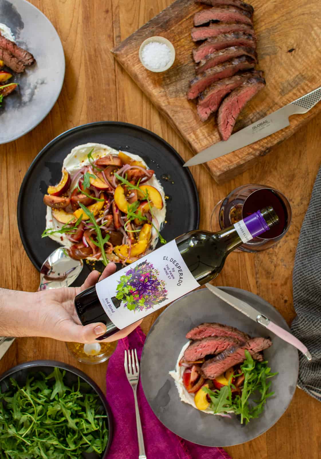 someone pouring El Desperado wine with plates of food below 