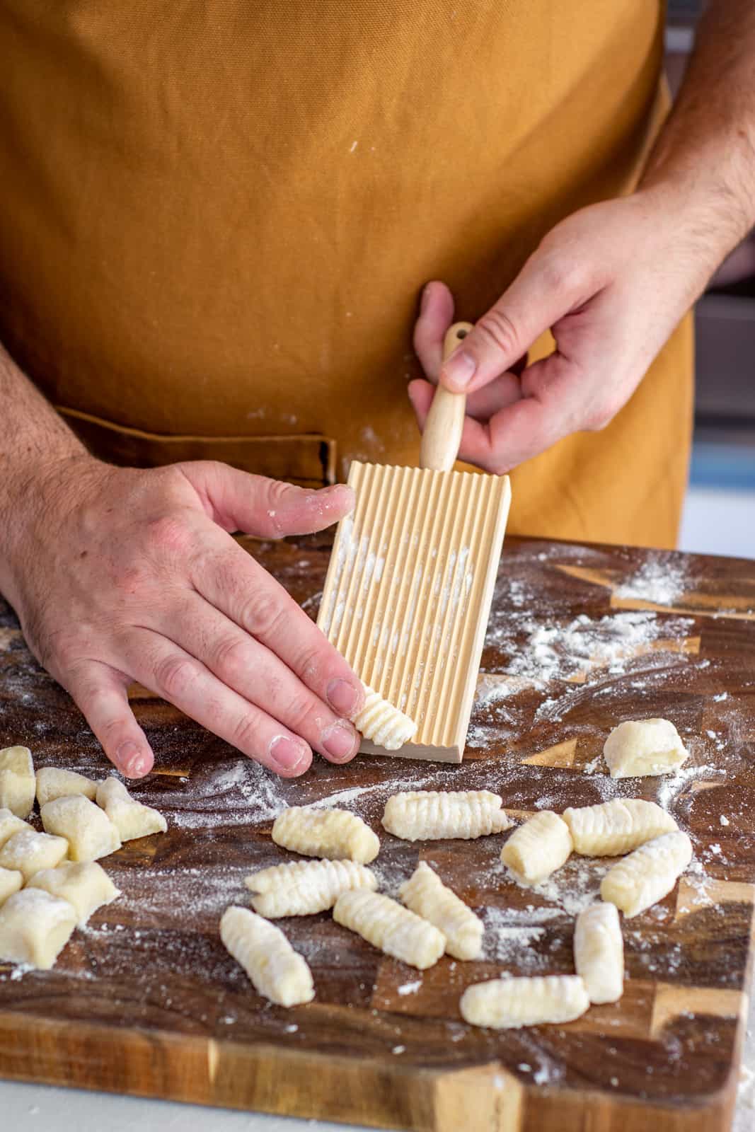 someone rolling gnocchi on gnocchi board 