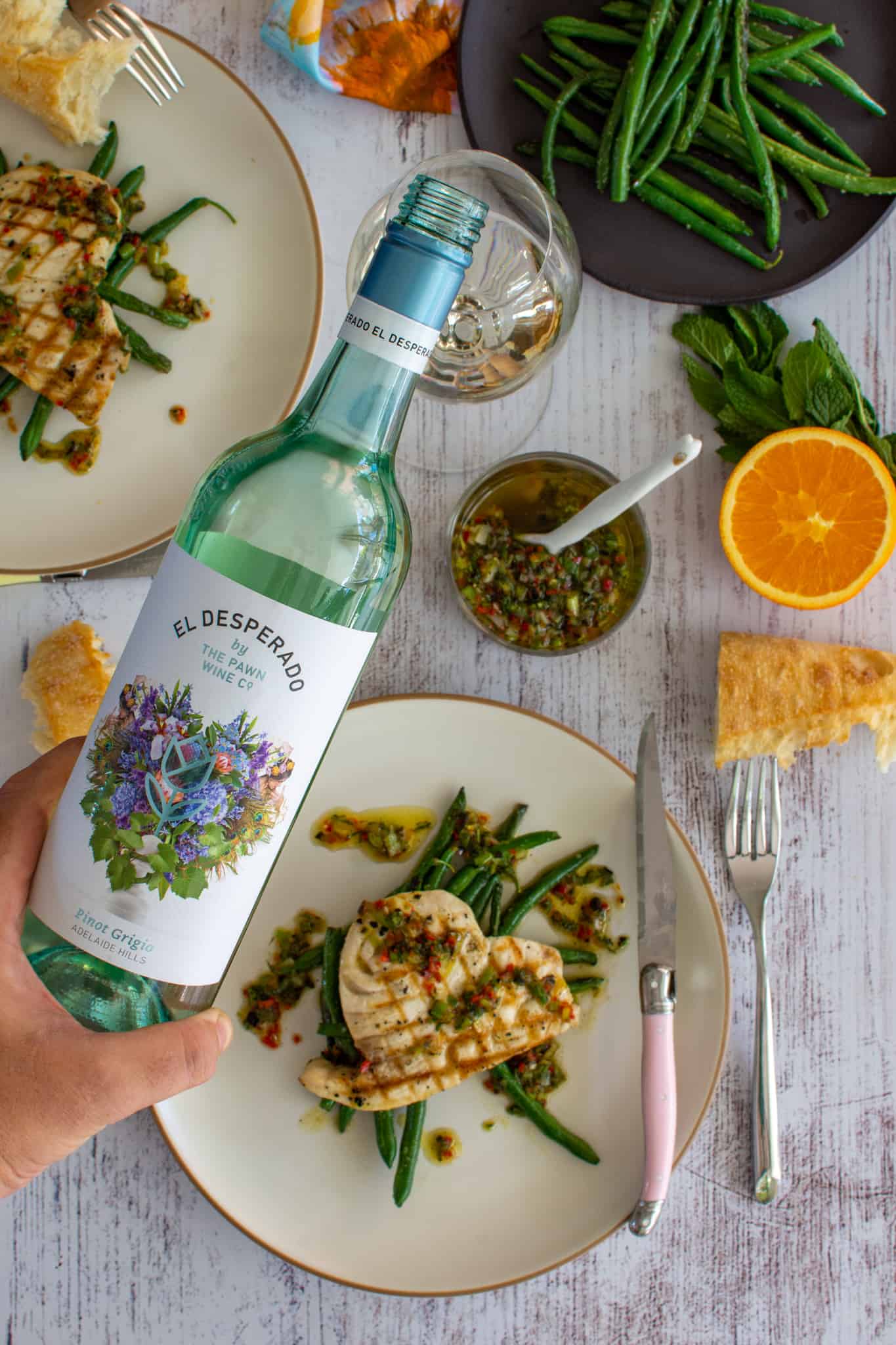 someone pouring wine with plates of grilled swordfish below 
